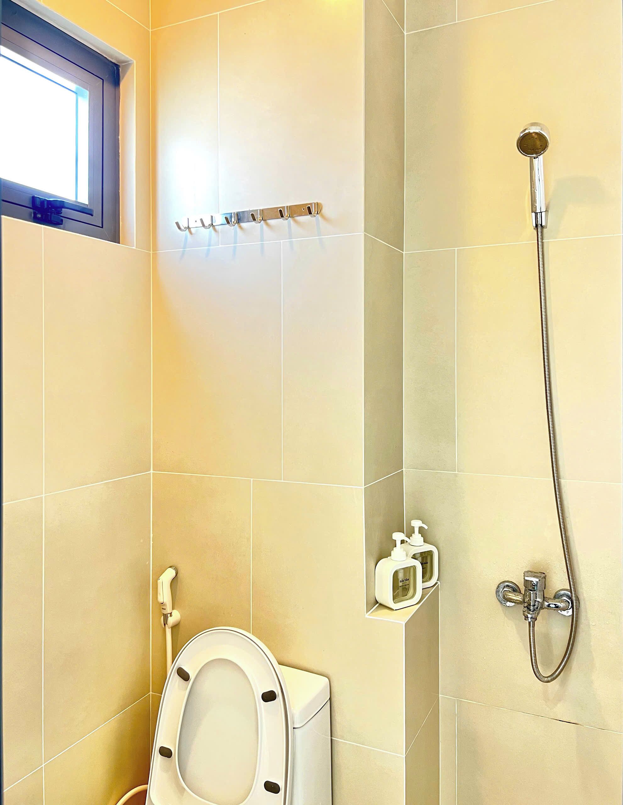 Un baño con inodoro, ducha y ventana.