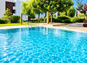 Una piscina cristalina con un muelle de madera y un letrero.