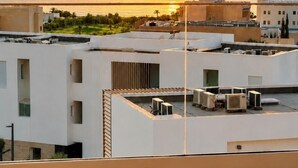 Une terrasse sur le toit équipée de climatiseurs, avec vue sur la mer et des bâtiments en arrière-plan.