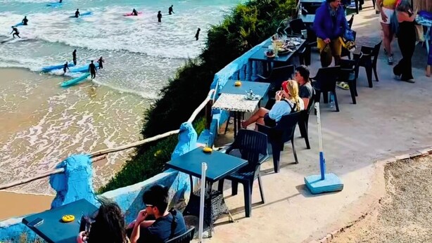 Un restaurant en bord de mer avec une terrasse offrant une vue sur l’océan, une salle à manger et une vue sur la plage.