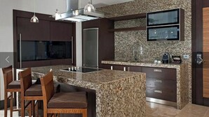 Una cocina moderna con encimeras de granito, electrodomésticos de acero inoxidable y un televisor integrado.