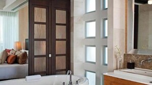 Un baño moderno con una bañera independiente, un tocador de madera y un espejo grande.