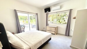 A bedroom with a bed, a TV, a dresser, and a window with curtains. - Villa with lagoon pool 10 minutes from the center (El Limón)
