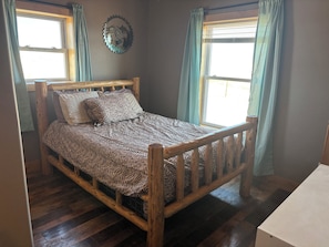 Un lit en bois avec une couvre-lit à motifs zébrés, deux oreillers et un élément décoratif mural.