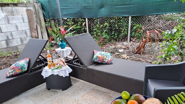 A patio area with wicker furniture, a table with drinks and snacks, and a bowl of fruit. - Stay at Villa Désiré, located in Le Vauclin, south of Martinique. (Le VAUCLIN)