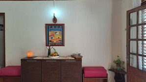 A room with a wooden ceiling, a framed poster on the wall, a small table with a fruit bowl, a heater, and a bench with a cushion. - Stay at Villa Désiré, located in Le Vauclin, south of Martinique. (Le VAUCLIN)
