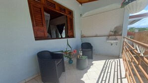 A balcony with two chairs, a small table, and a potted plant. - Stay at Villa Désiré, located in Le Vauclin, south of Martinique. (Le VAUCLIN)