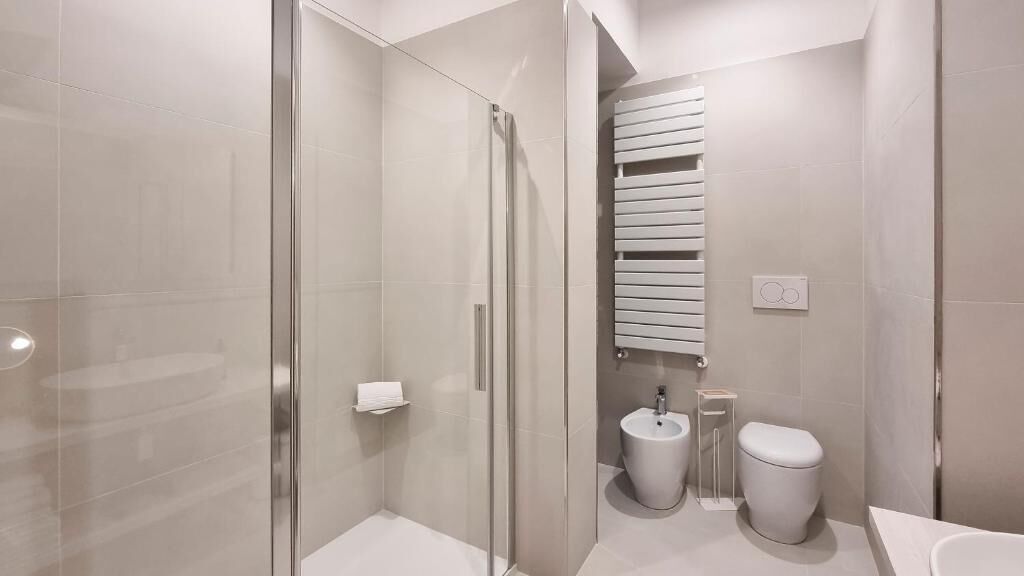 Un baño moderno con cabina de ducha de vidrio, inodoro, bidé y lavamanos.