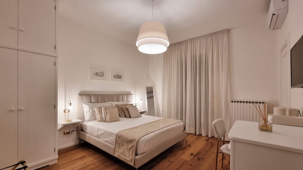A bedroom with a bed, bedside table, lamp, and a desk with a chair. - Casa FEREMI (Cavallino)