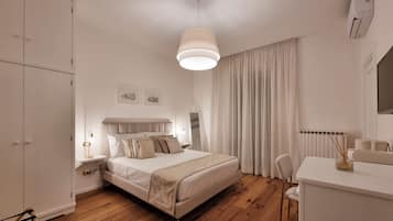 Ein Schlafzimmer mit Bett, Nachttisch, Lampe und Schreibtisch mit Stuhl.