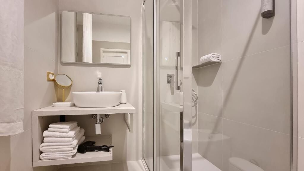 Un baño moderno con cabina de ducha de vidrio, un lavabo blanco y un espejo encima.