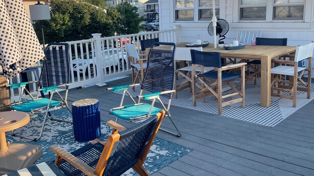 A deck with outdoor furniture, a table, and a covered area with a patterned umbrella. - CONDO 2 BEDRM, EXPANSIVE PRIVATE DECK! WALKABLE to all HOT SPOTS w/ POOL (Margate City)
