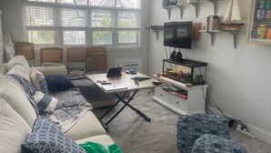 A modern living room with a sofa, a coffee table, a TV, and a fish tank. - CONDO 2 BEDRM, EXPANSIVE PRIVATE DECK! WALKABLE to all HOT SPOTS w/ POOL (Margate City)
