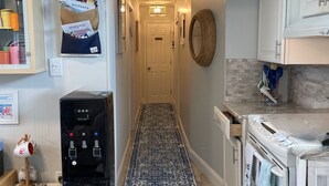 A kitchen with a coffee machine, a water dispenser, a stove, and a sign that reads 'BEACH HOUSE'. - CONDO 2 BEDRM, EXPANSIVE PRIVATE DECK! WALKABLE to all HOT SPOTS w/ POOL (Margate City)