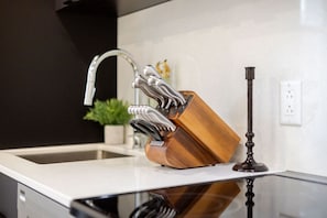 A kitchen with a modern faucet, a wooden knife block, and a glass countertop. - Historic Hideaway – Bright Apartment in Old Montreal (Montréal)
