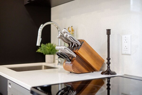 Una cocina con un grifo moderno, un bloque de cuchillos de madera y una encimera de vidrio.
