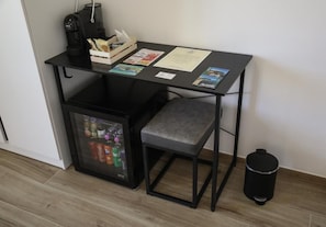 A compact kitchenette with a coffee maker, a small fridge with beverages, a chair, and a trash bin. - Affittacamere Brezza Di Sirolo (Sirolo)