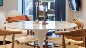 Zona pranzo con tavolo rotondo, sedie in legno e un vaso con candele.
