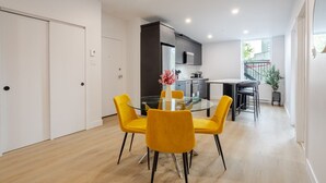 A modern kitchen with a dining area featuring a glass table and yellow chairs. - Stylish Downtown Retreat (Montreal)