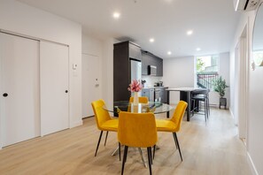 Eine moderne Küche mit Essbereich, inklusive Glastisch und gelber Stühle.