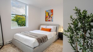 A bedroom with a bed, a window, a painting, and a potted plant. - Stylish Downtown Retreat (Montreal)
