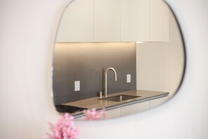 A modern kitchen with a stainless steel sink, a curved faucet, and a minimalist design. - Modern Retreat with Chic Design in Downtown MTL (Montreal)