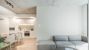 A modern apartment with a kitchen, dining area, and a grey sectional sofa. - Urban Chic Stay with Skyline Views (Montreal)
