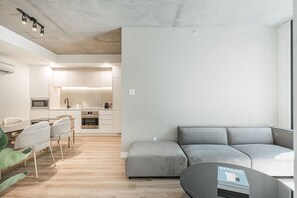 A modern apartment with a kitchen, dining area, and a grey sectional sofa. - Urban Chic Stay with Skyline Views (Montreal)