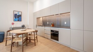 Une cuisine moderne avec une table à manger ronde et des chaises, des appareils électroménagers intégrés et un design minimaliste.
