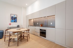 Une cuisine moderne avec une table à manger ronde et des chaises, des appareils électroménagers intégrés et un design minimaliste.