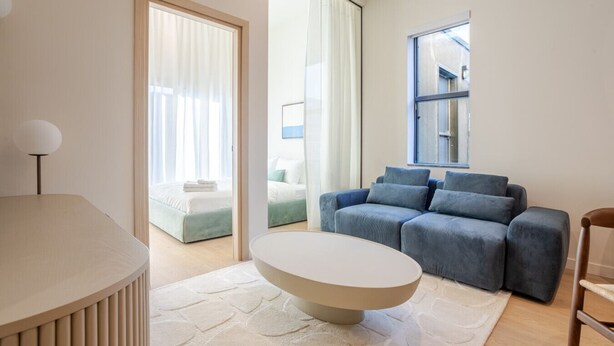 Un salon moderne avec un canapé, une table basse ronde et un lit agrémenté d’une touche de vert.