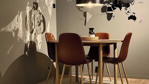 A dining area with a round table, chairs, a hanging light fixture, and a wall map. - Renovated Apartment High Standard to City Center, Park (Tromsø)