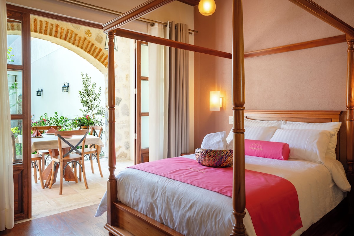 A four-poster bed with a white and pink bedspread, a woven basket, and a wooden headboard.