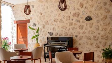 Una habitación con piano, pared de piedra y disposición de asientos.