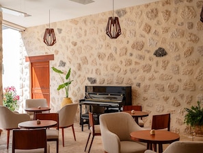A room with a piano, stone wall, and seating arrangement.