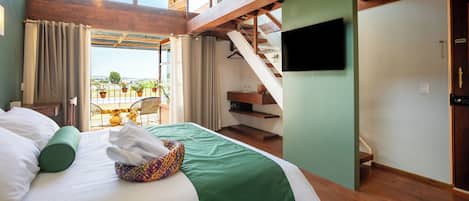 Una habitación de hotel con cama, televisión, balcón con plantas en macetas y una escalera.