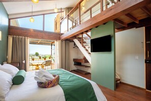 A hotel room with a bed, a TV, a balcony with potted plants, and a staircase. - Corazante Hotel Gallery (San Andres Cholula)