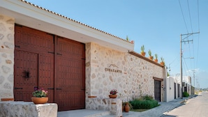 A building with a stone facade, large wooden doors, and potted plants. - Corazante Boutique Hotel (San Andrés Cholula)