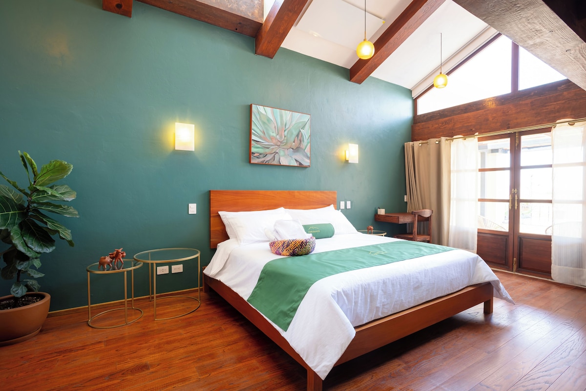 A hotel room with a wooden bed, a green wall, and a large window.