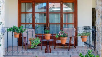 Eine Terrasse im Freien mit Tisch und Stühlen, umgeben von Topfpflanzen und einem Steinplattenboden.