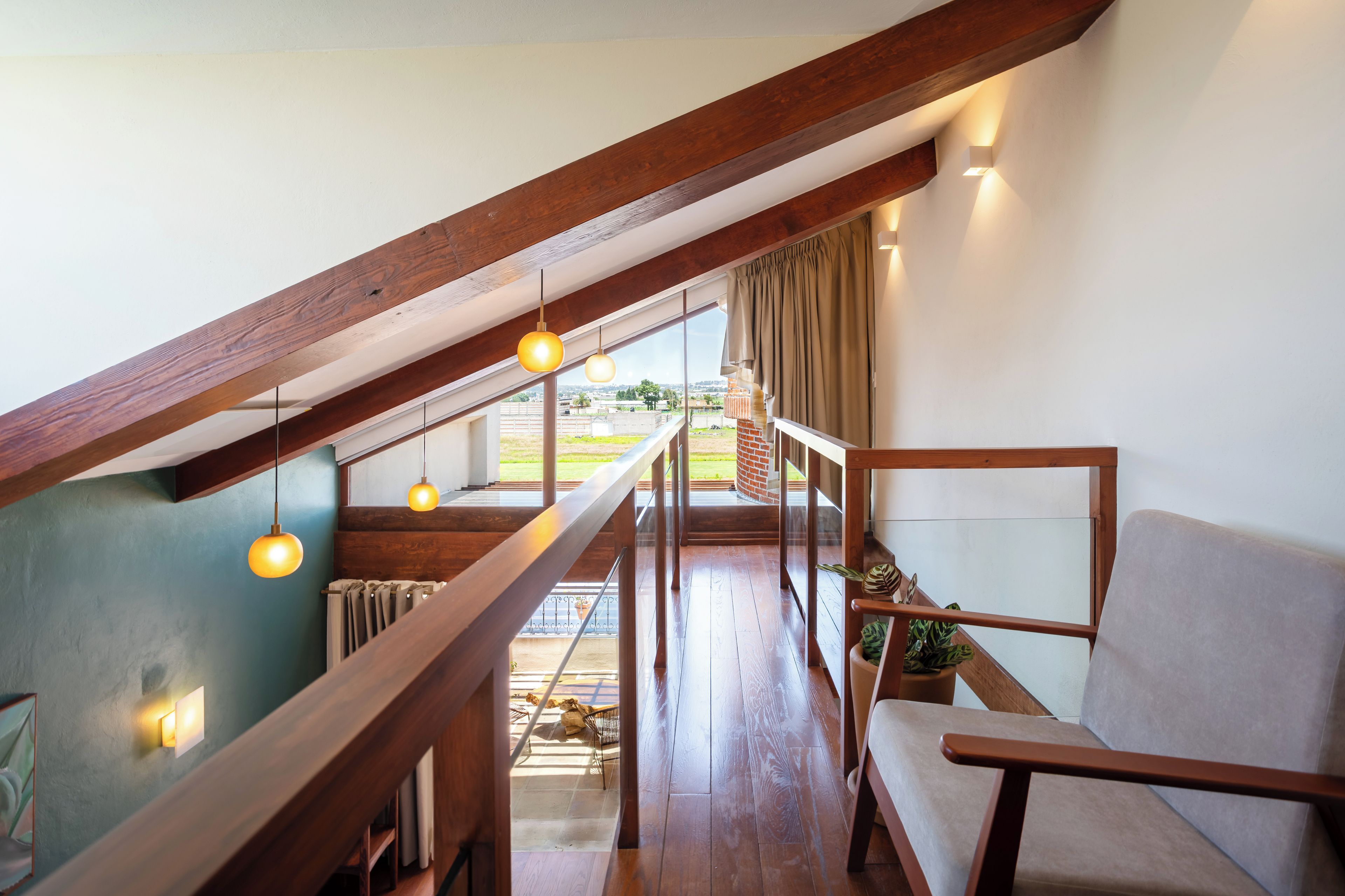 Ein Loft-Zimmer mit einer Holztreppe, einer Couch und hängenden Pendelleuchten.