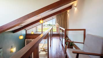 Ein Loft-Zimmer mit einer Holztreppe, einer Couch und hängenden Pendelleuchten.