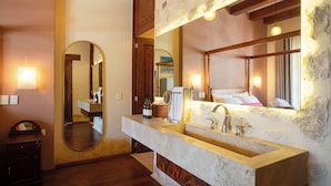 A bathroom with a large mirror, a sink with a marble countertop, and wooden beams on the ceiling. - Corazante Boutique Hotel (San Andrés Cholula)