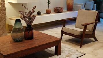 Een moderne woonkamer met een houten salontafel, een beige fauteuil en een witte bank.