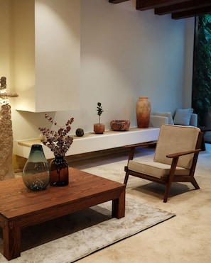 Una sala de estar moderna con una mesa de centro de madera, un sillón color beige y un sofá blanco.