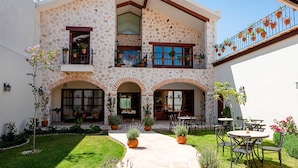 A two-story building with a stone facade, multiple balconies with potted plants, and outdoor seating areas. - Corazante Boutique Hotel (San Andrés Cholula)