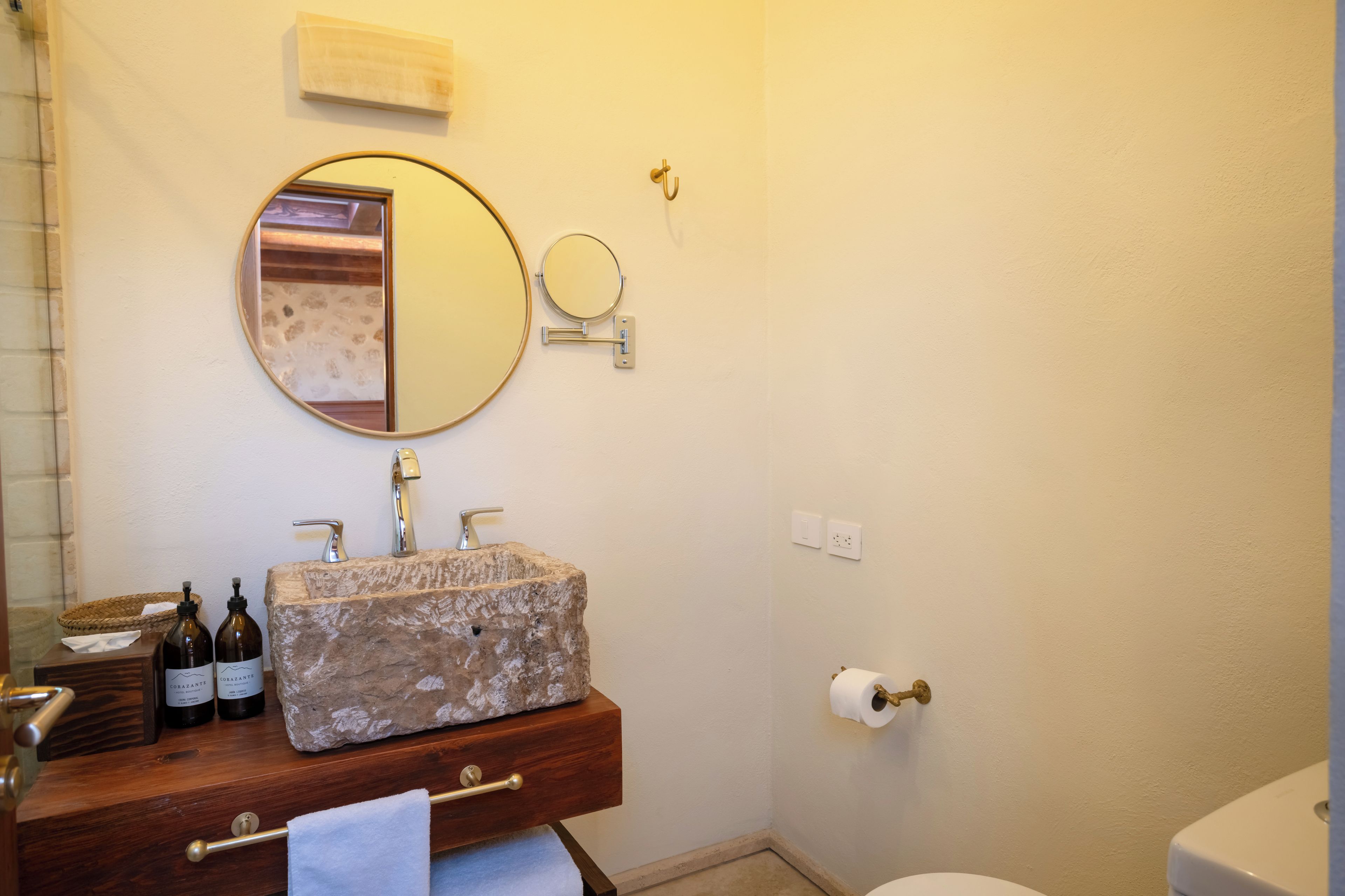 Une salle de bain avec un lavabo en pierre, un miroir, un porte-serviettes et des toilettes.