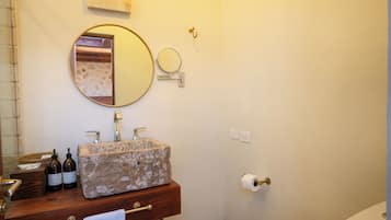 Une salle de bain avec un lavabo en pierre, un miroir, un porte-serviettes et des toilettes.