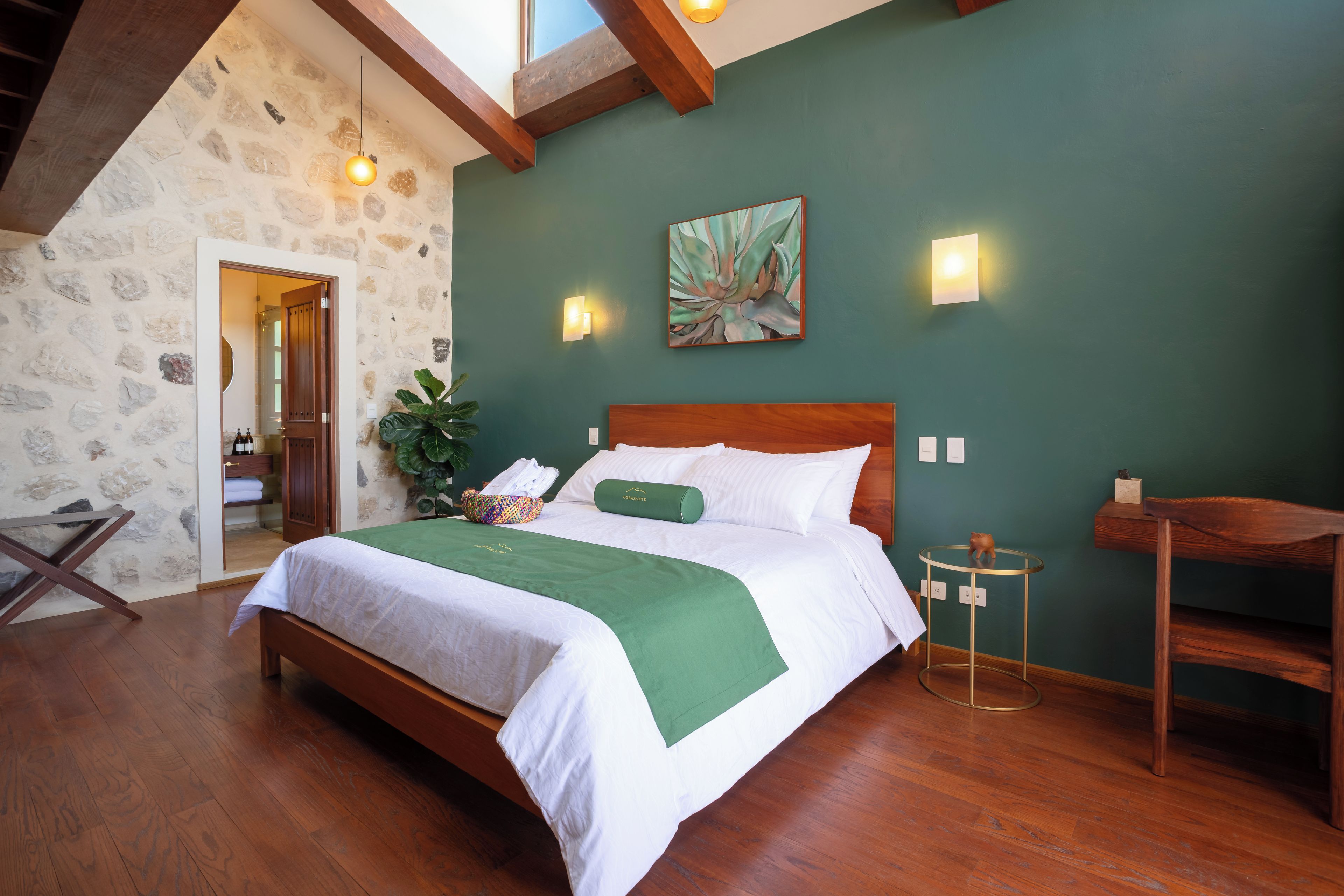 A bedroom with a wooden bed, a green wall, and a stone wall.