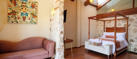 Un dormitorio con una cama con dosel, un sofá rosa, un cuadro en la pared y una pared de piedra.